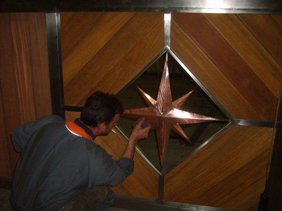 Una persona ammira una stella di rame montata su un pannello di legno a muro.