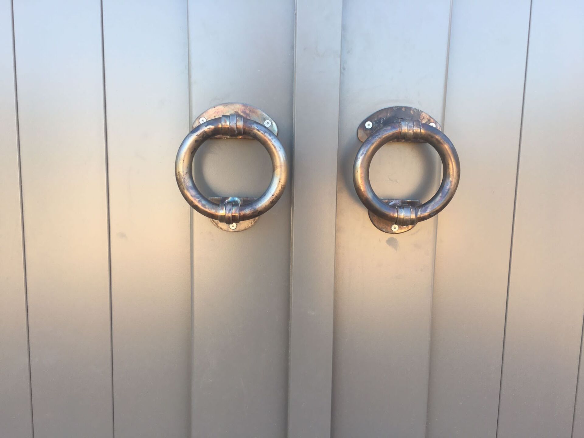 Due maniglie ad anello in metallo su una porta doppia grigio chiaro