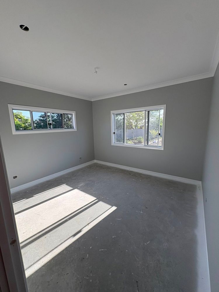 A bedroom with a window and grey painted walls