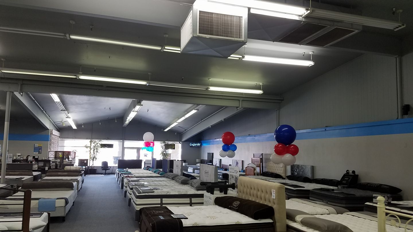 A mattress store filled with lots of beds and balloons.
