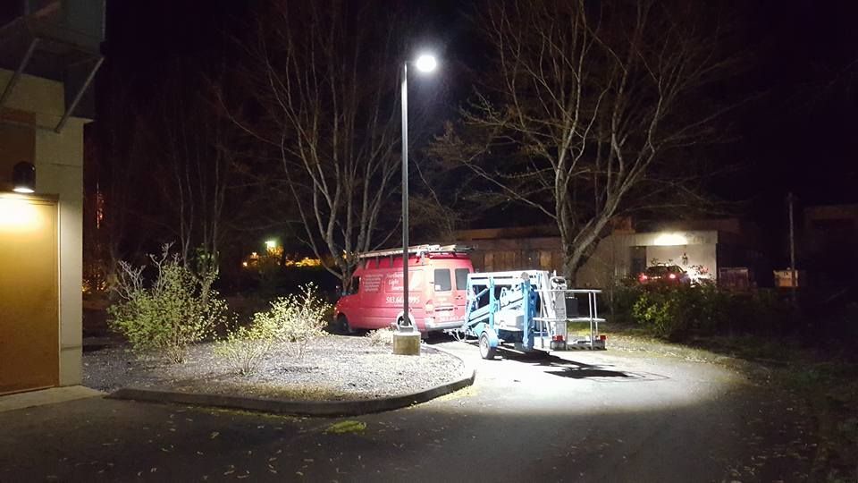 A red van is parked in a parking lot at night.
