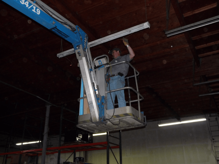 A man is standing on a lift with the number 34/19 on it