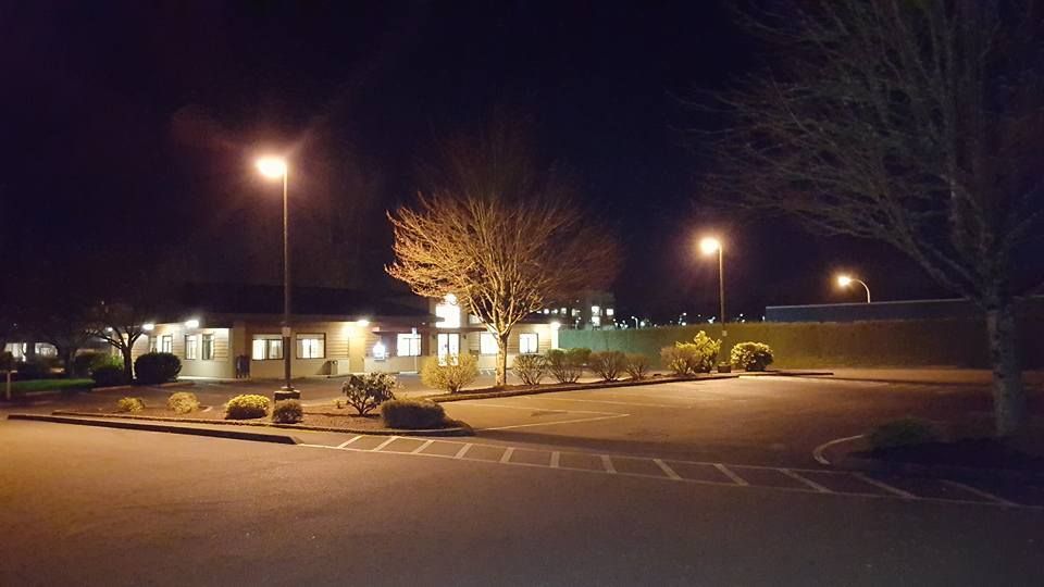 A parking lot is lit up at night with a building in the background.
