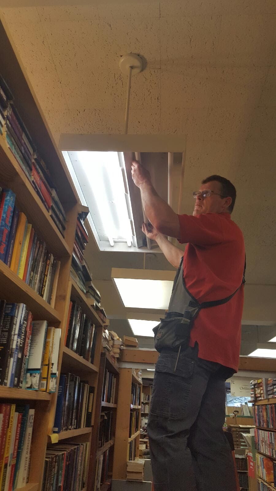 A man is fixing a lamp on the ceiling with a screwdriver.