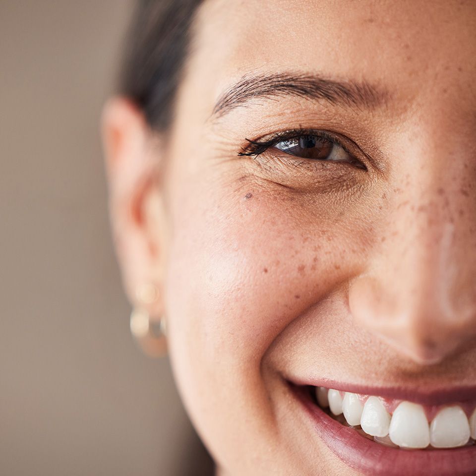 A close up of a woman 's face with freckles smiling.
