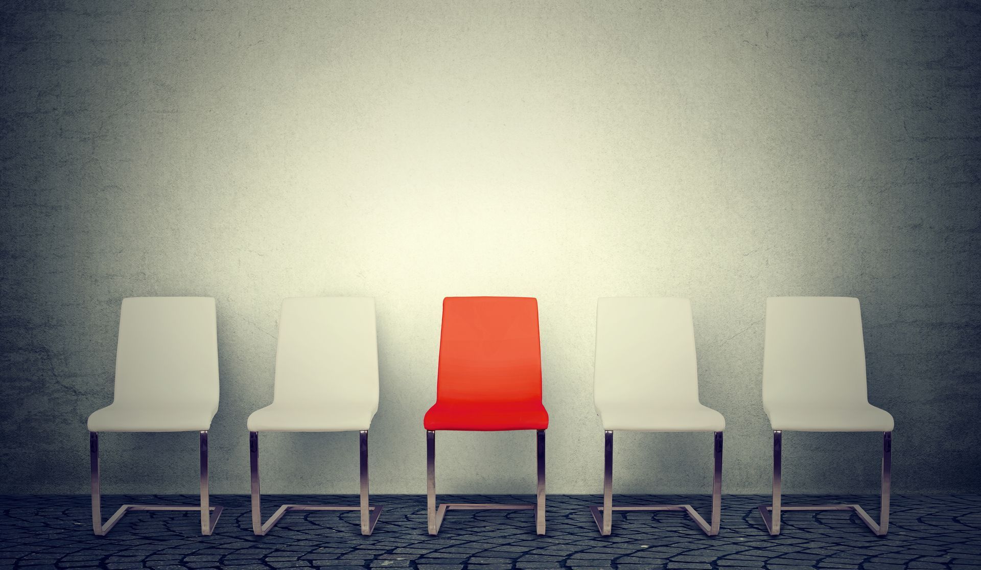 A row of white chairs with a red chair in the middle.