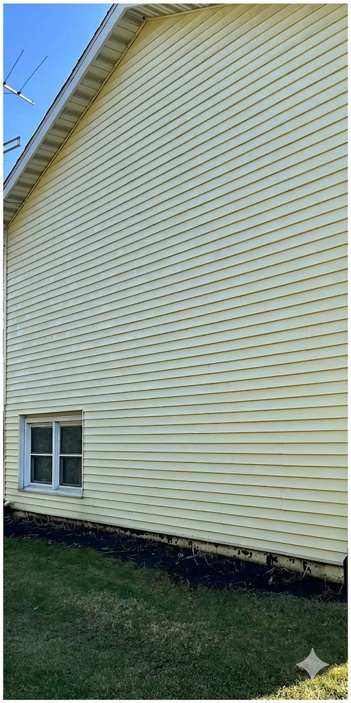 White vinyl-sided house exterior with two windows and a grass strip at the base