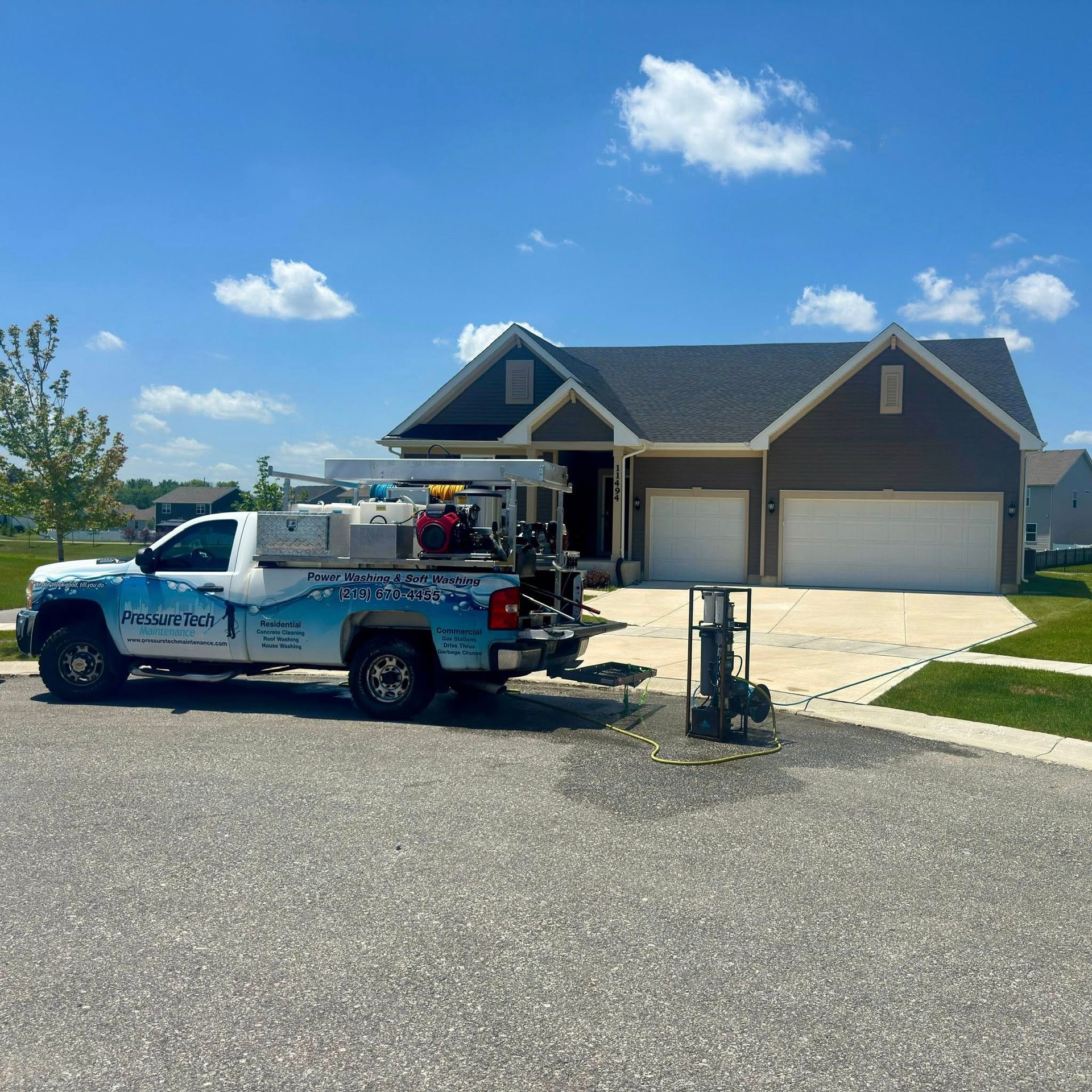 Blue pickup truck parked in front of a suburban house with a three-car garage on a sunny day