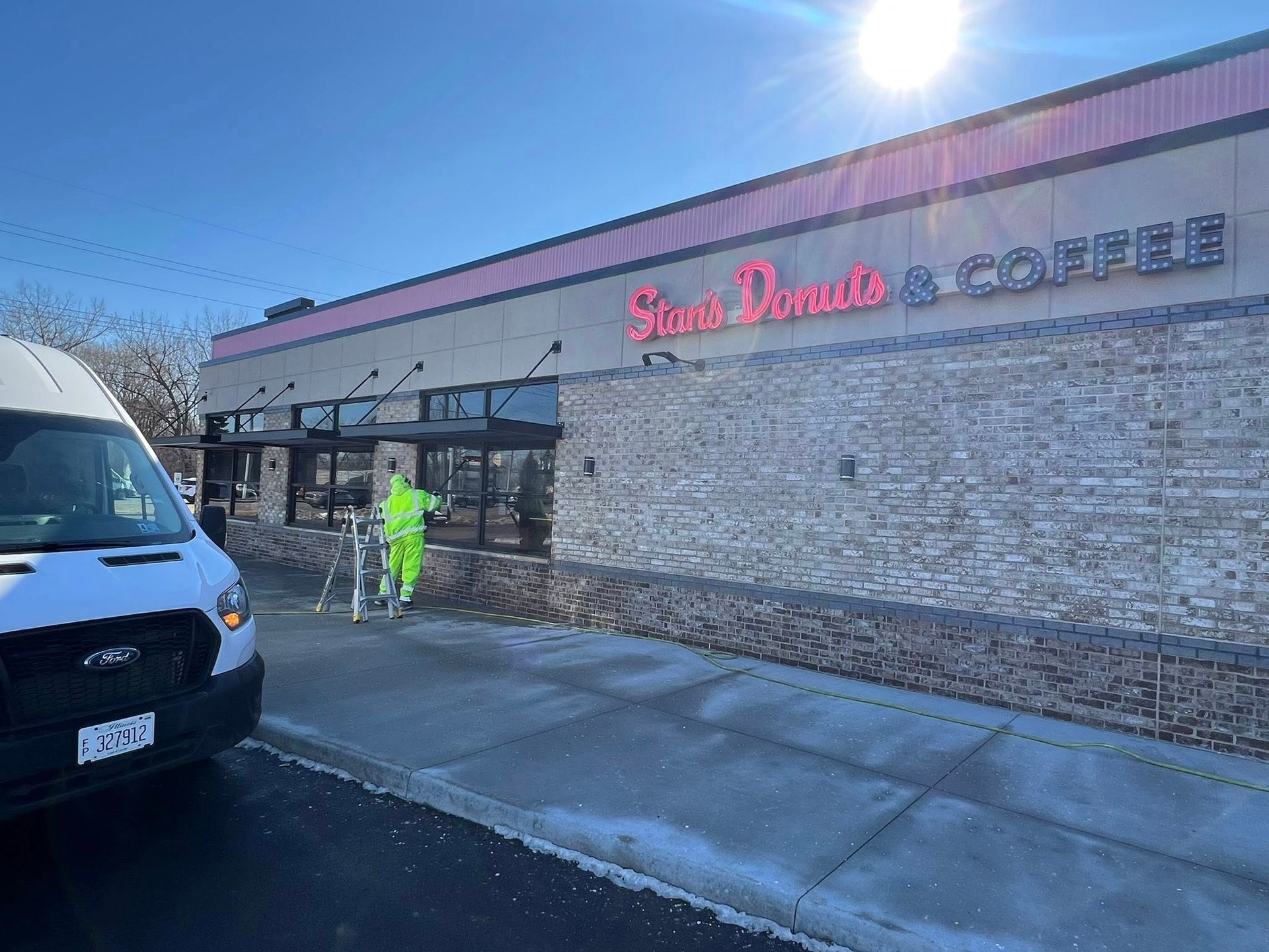 Snow Bros. Coffee storefront with a worker in neon safety gear beside a parked van on a sunny day
