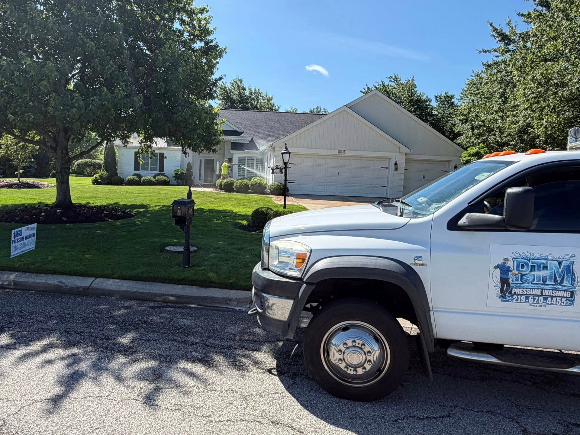 Suburban house with lawn and mailbox, partially blocked by a white pickup truck in the foreground.