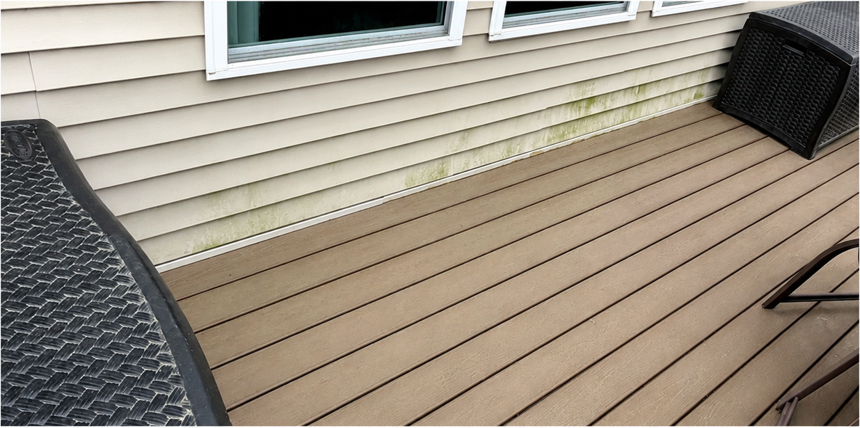 Outdoor deck with tan composite boards and black wicker chairs beside a house window