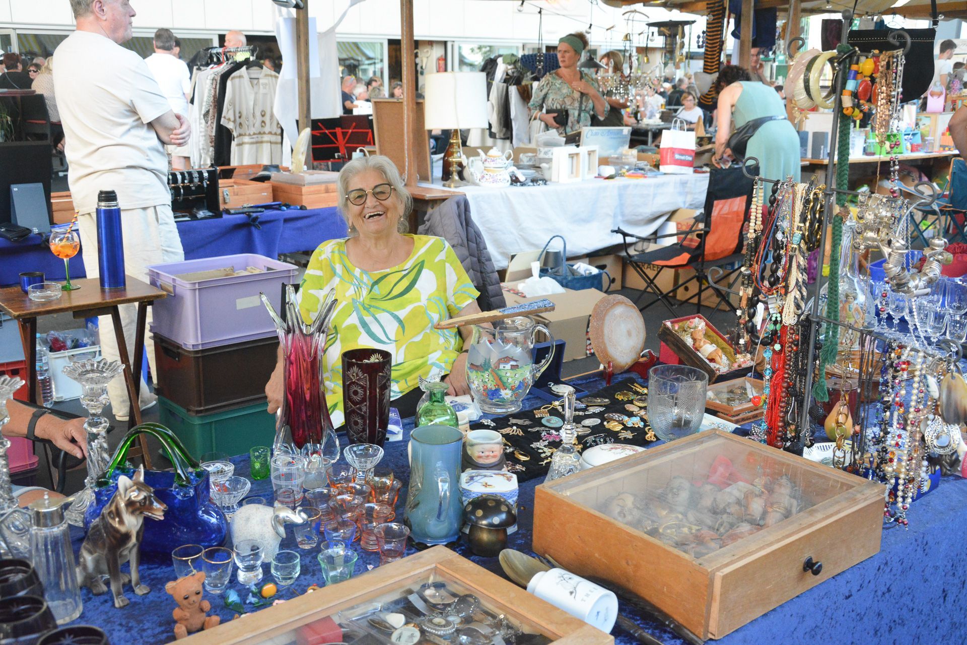 Eine Frau sitzt an einem Tisch auf einem Flohmarkt
