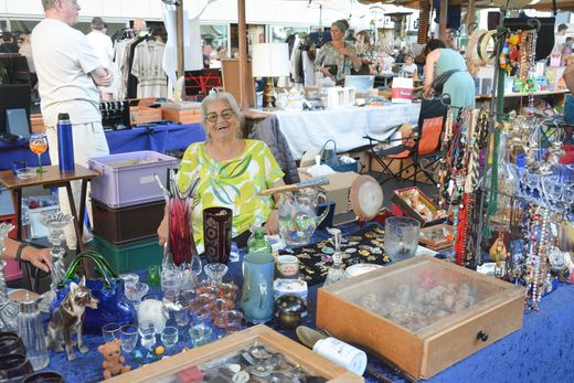 Eine Frau sitzt an einem Tisch auf einem Flohmarkt