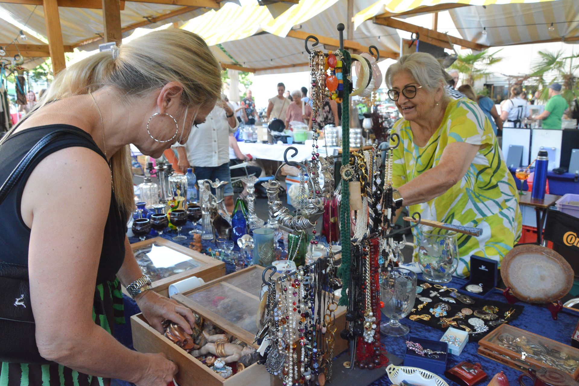 Zwei Frauen schauen sich auf einem Flohmarkt Schmuck an.