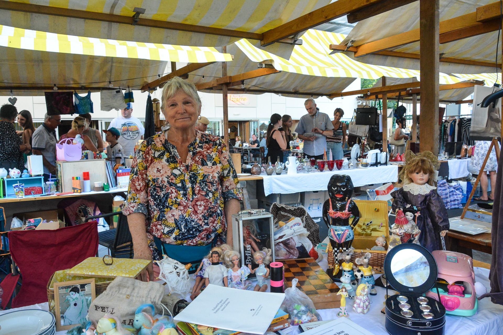 Eine Frau steht vor einem Tisch auf einem Flohmarkt.