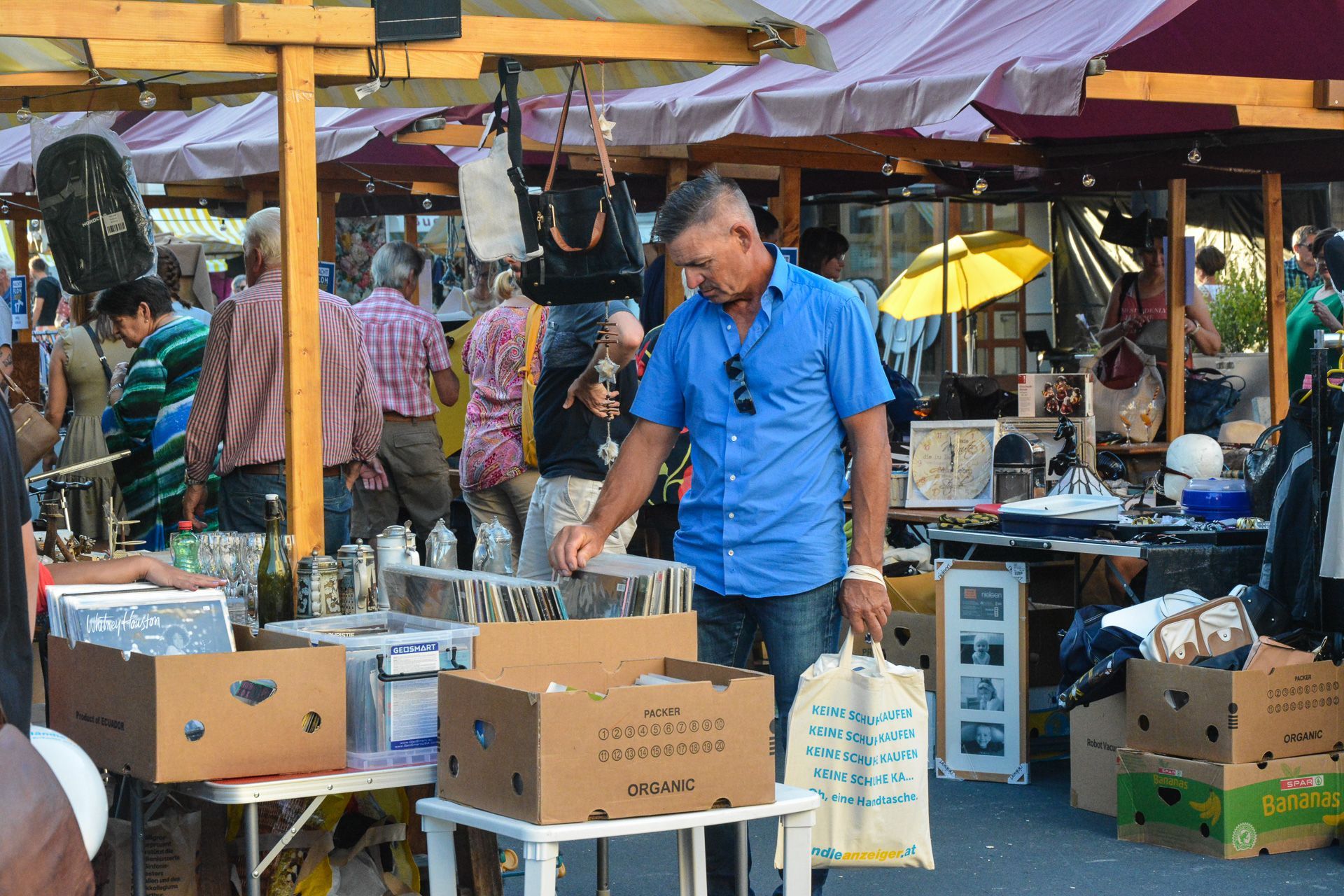 Ein Mann in einem blauen Hemd kauft auf einem Flohmarkt ein