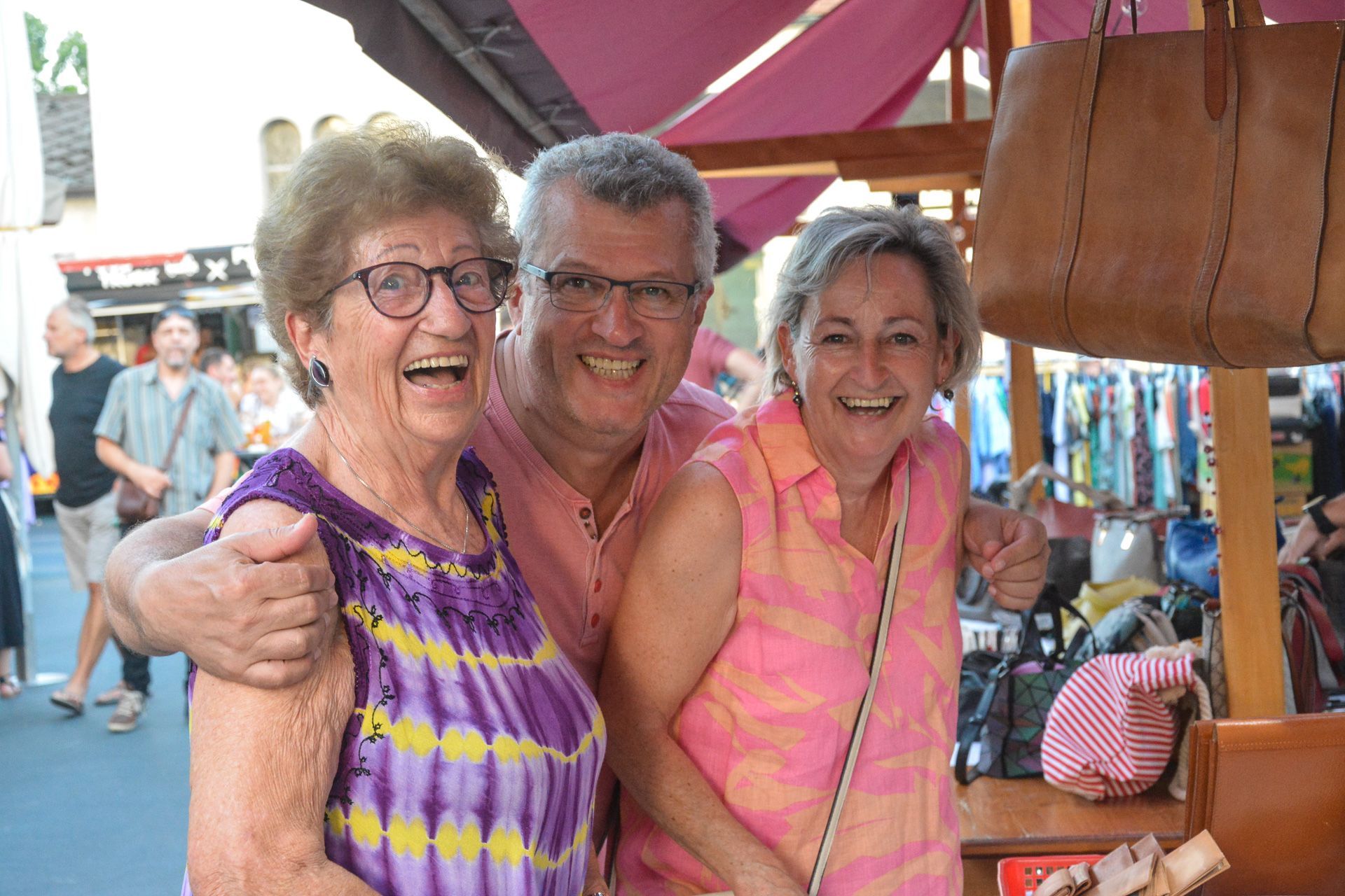 Ein Mann und zwei Frauen posieren auf einem Markt für ein Foto.