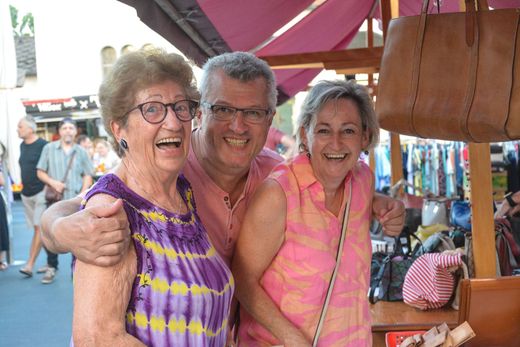 Ein Mann und zwei Frauen posieren auf einem Markt für ein Foto.