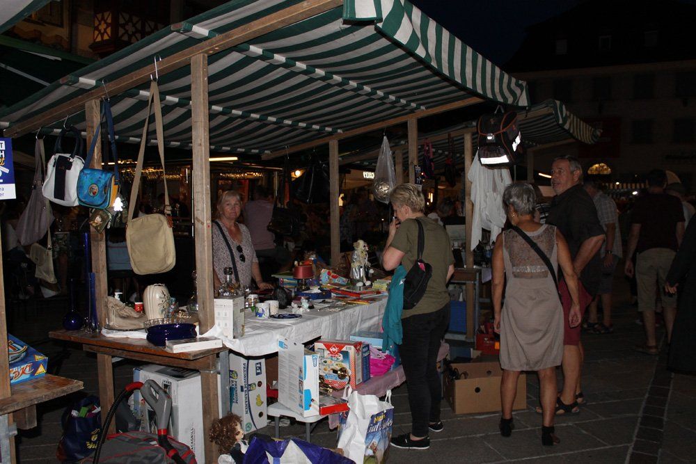 Eine Gruppe von Menschen steht nachts um einen Marktstand herum.