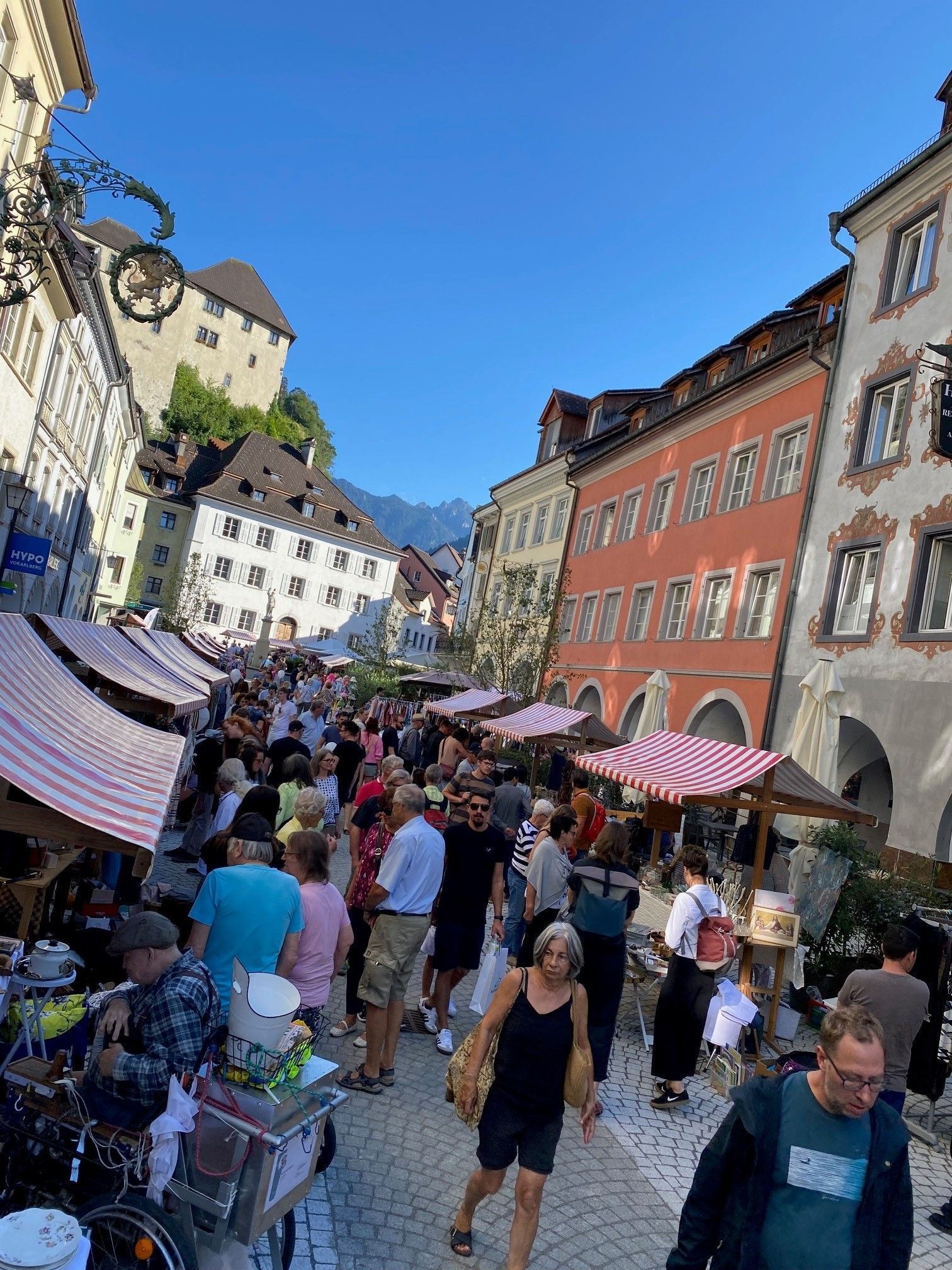 Eine Menschenmenge geht eine Straße vor einem Gebäude entlang.