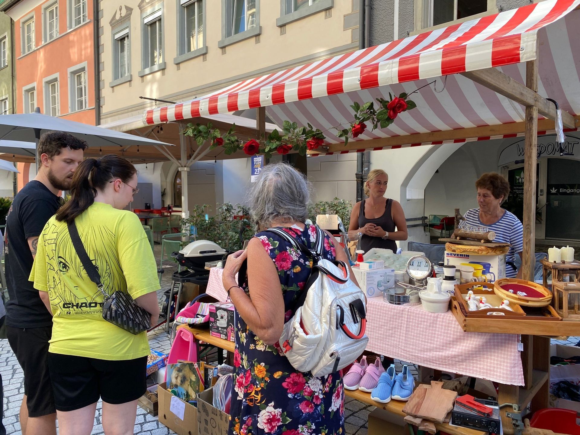Eine Gruppe von Menschen steht um einen Marktstand herum.