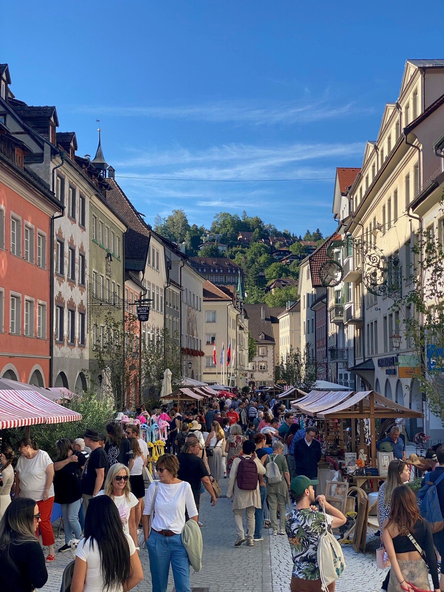 Eine Menschenmenge geht eine belebte Straße in einer Stadt entlang.