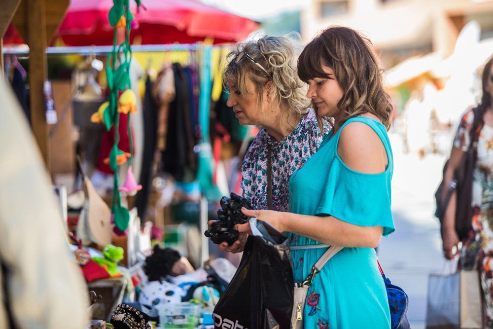 Zwei Frauen schauen sich auf einem Markt Kleidung an.