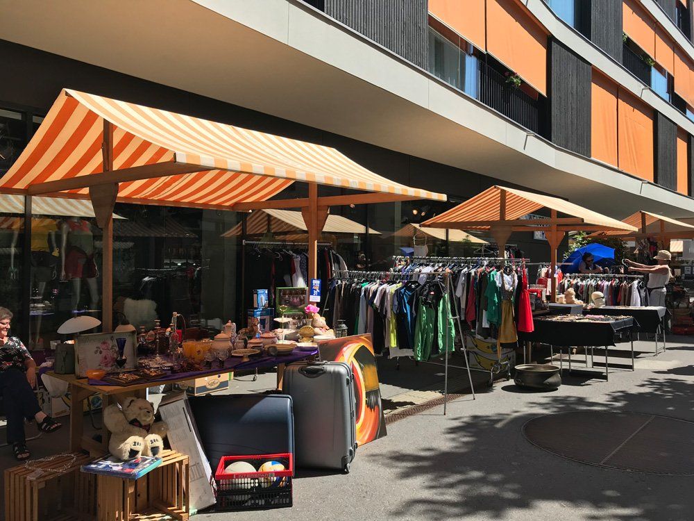 Ein Markt mit Tischen und Sonnenschirmen vor einem Gebäude.