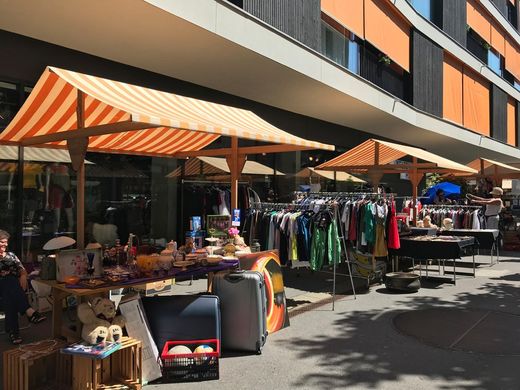 Ein Markt mit Tischen und Sonnenschirmen vor einem Gebäude.