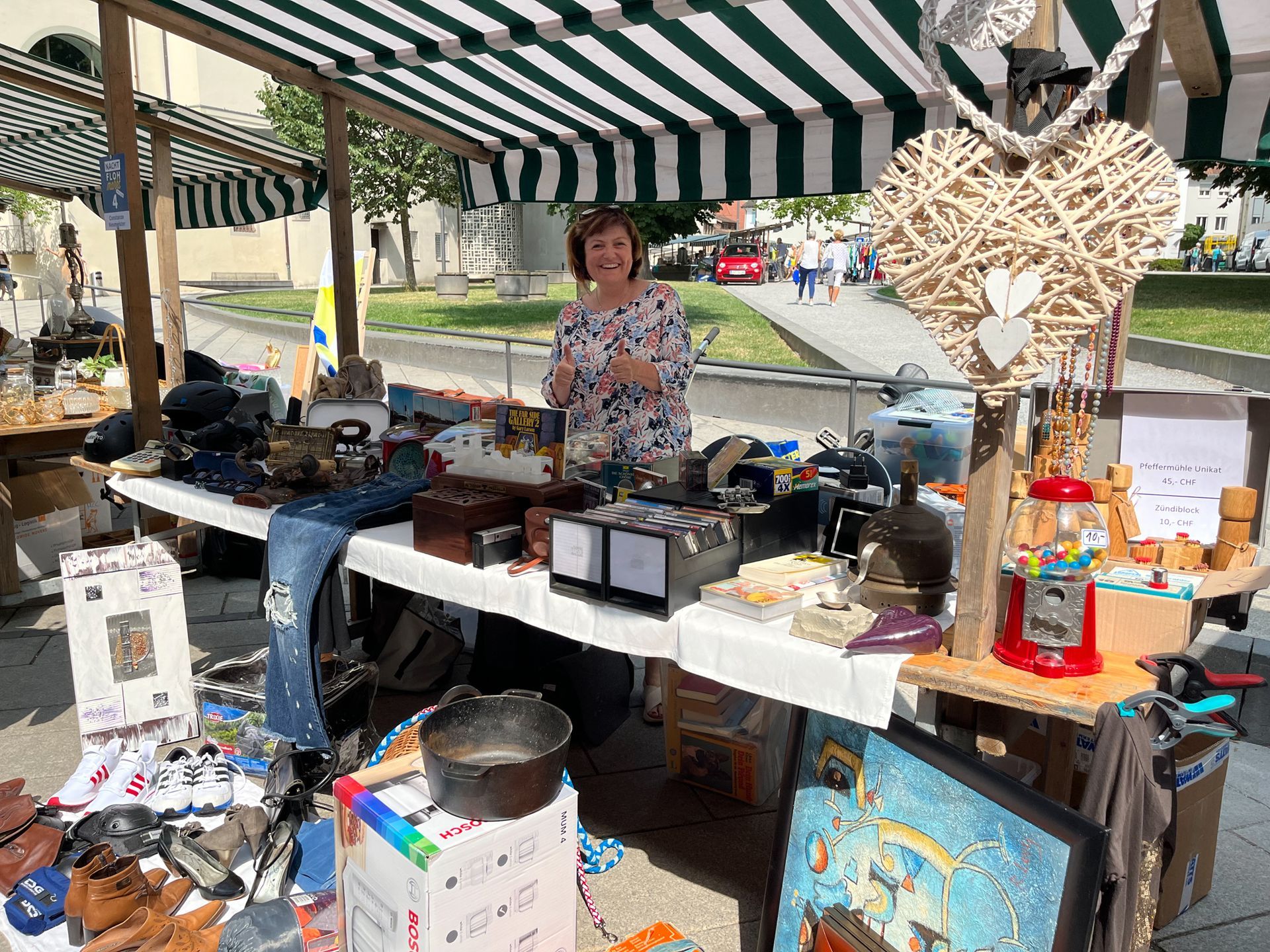 Eine Frau steht hinter einem Tisch auf einem Flohmarkt.