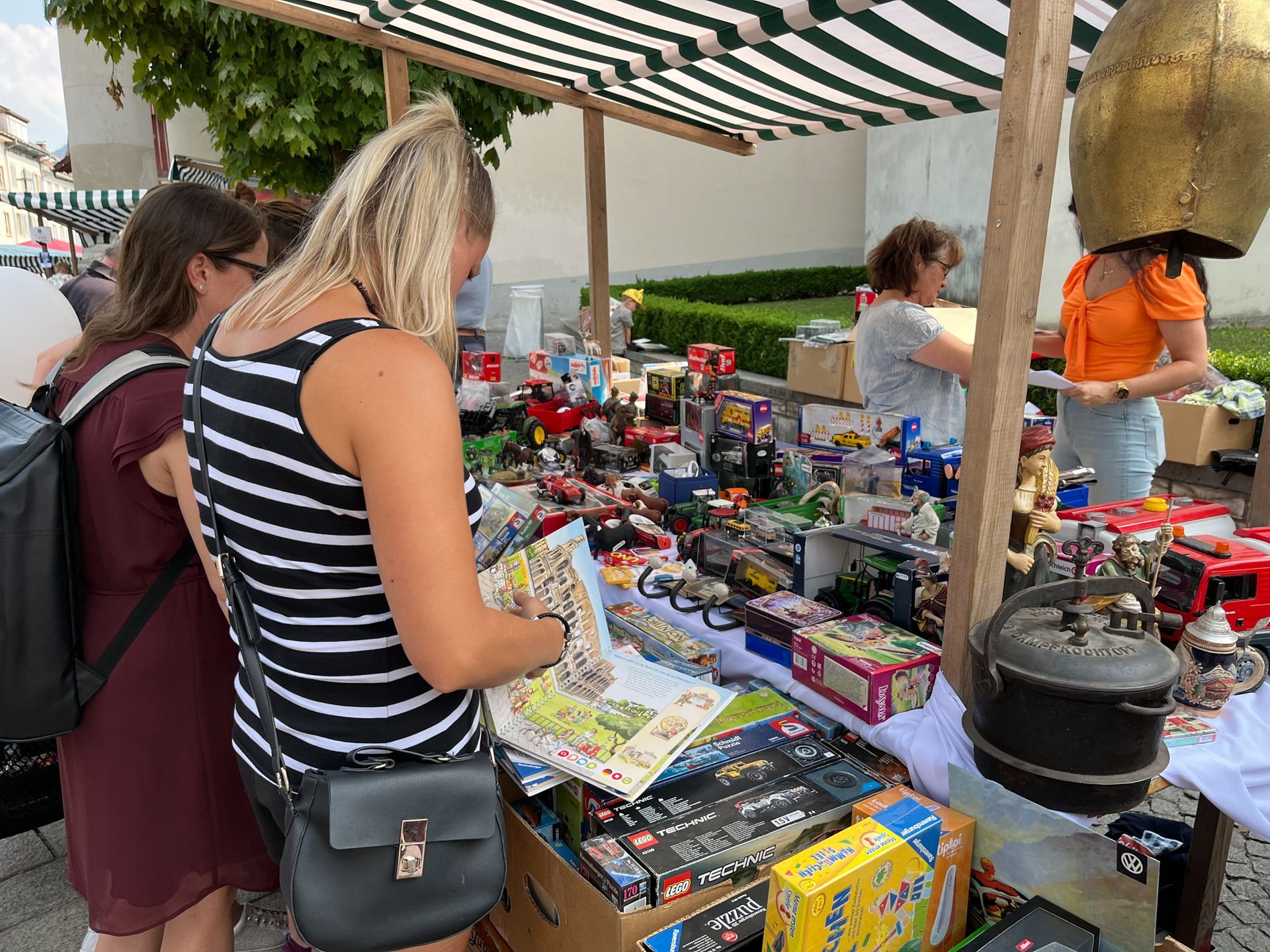 Eine Frau sieht sich auf einem Flohmarkt ein Buch an.