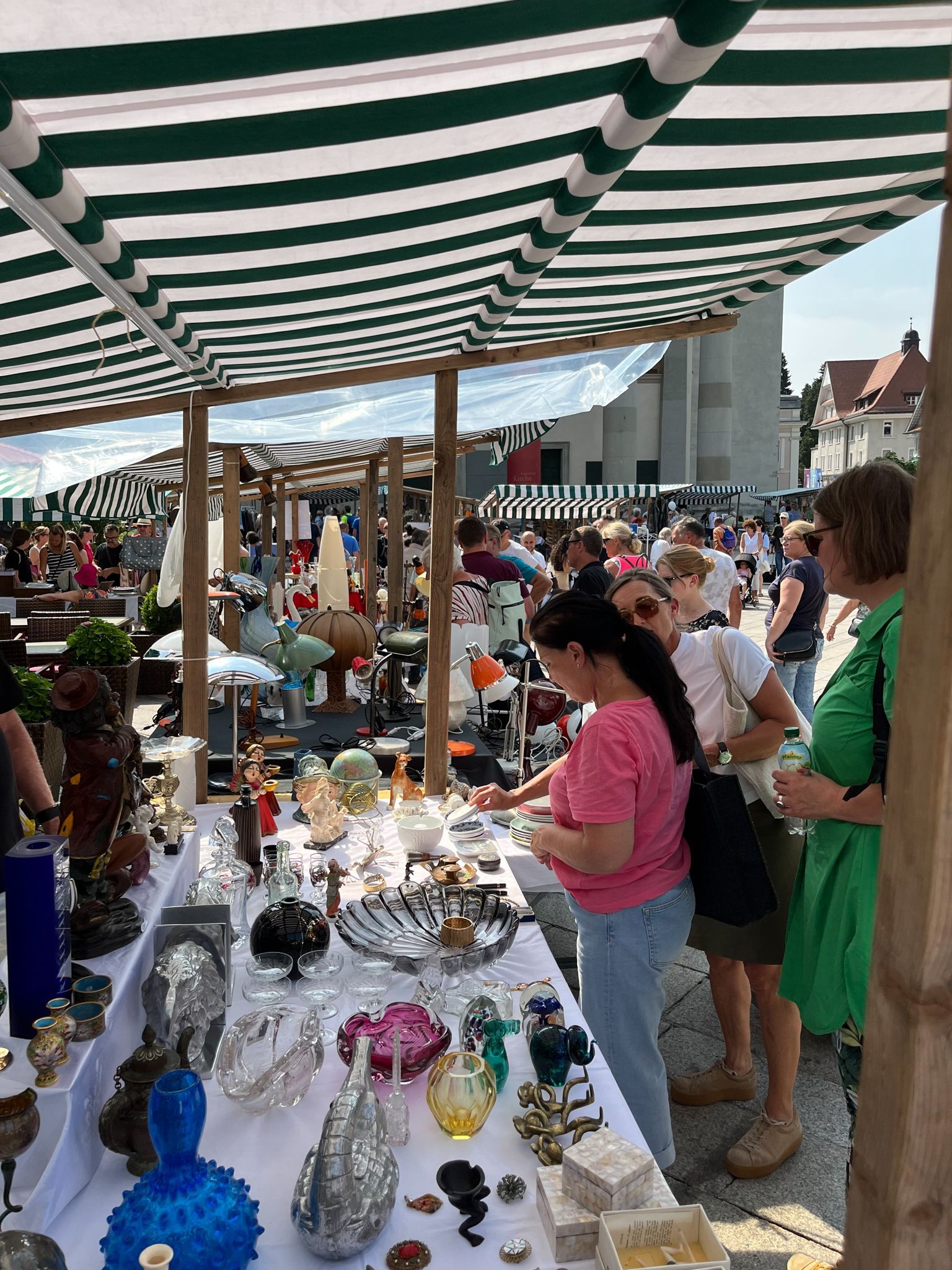 Auf einem Flohmarkt steht eine Gruppe von Menschen um einen Tisch herum.