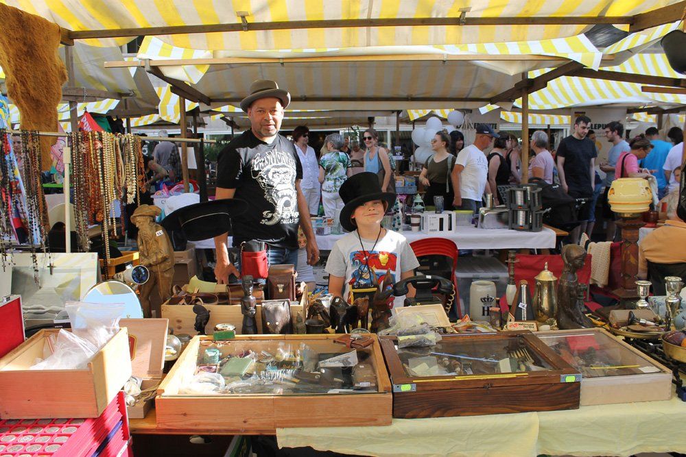 Ein Mann und ein Junge stehen auf einem Flohmarkt hinter einem Tisch.