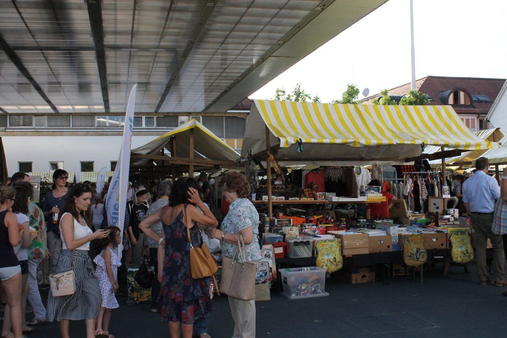 Eine Gruppe von Menschen geht auf einem Markt unter einer Brücke einkaufen.