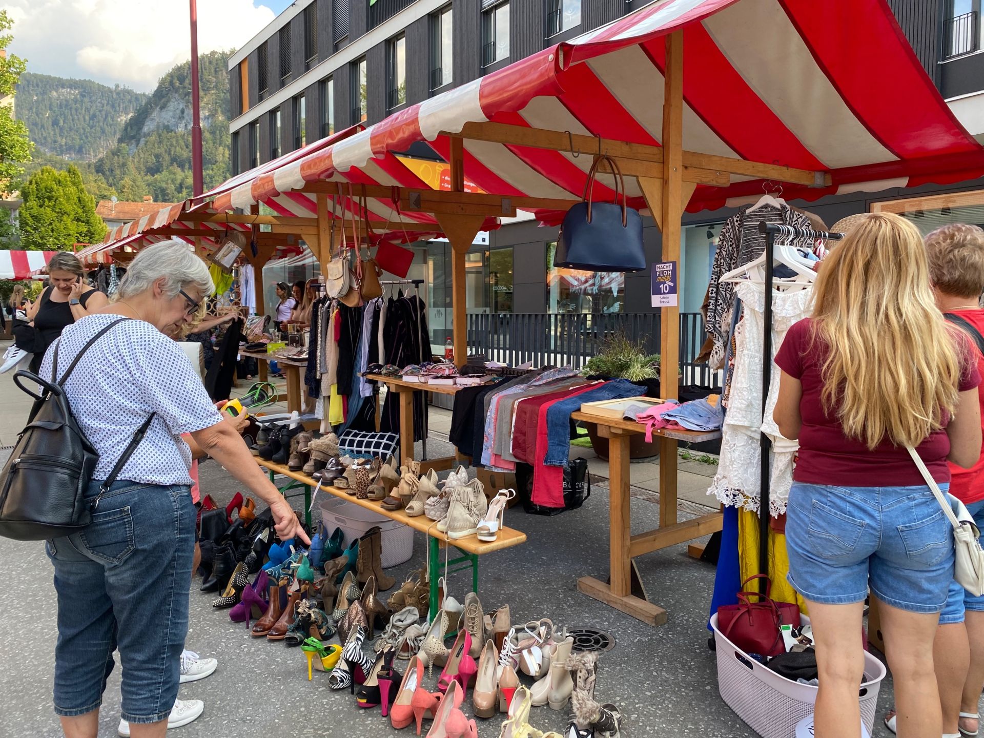 Eine Gruppe von Menschen steht um einen Stand auf einem Flohmarkt herum.