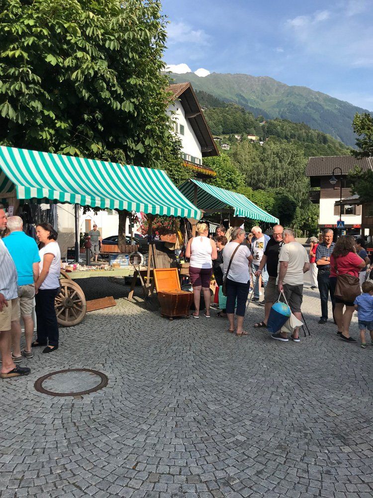 Eine Gruppe von Menschen steht vor einem grün-weiß gestreiften Zelt.