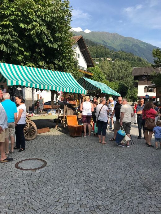 Eine Gruppe von Menschen steht vor einem grün-weiß gestreiften Zelt.