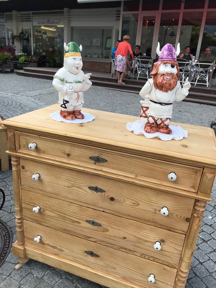 Zwei Wikingerfiguren sitzen auf einer Holzkommode.