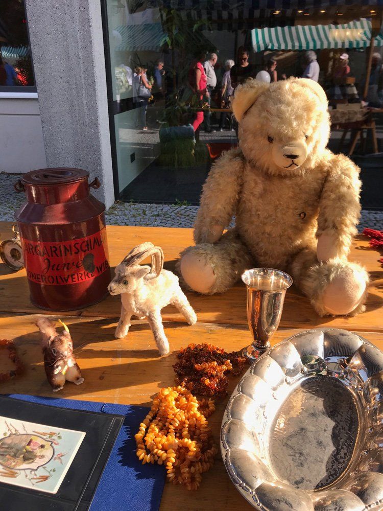 Ein Teddybär sitzt auf einem Holztisch neben einer Vase.