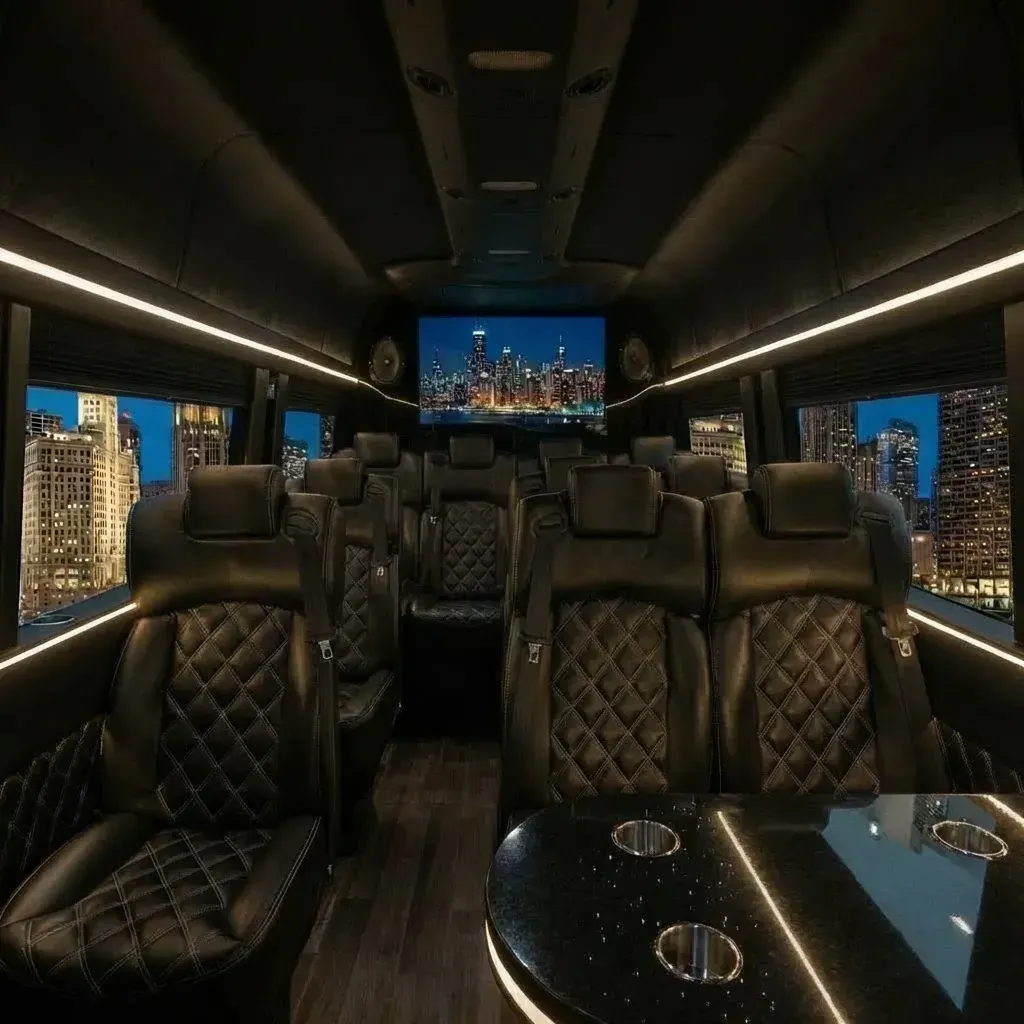 Inside of a black luxury van with leather seating, a large screen, and city views.