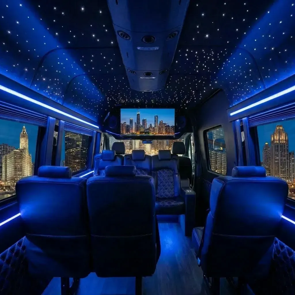 Interior of a luxury van with blue LED lighting, starry ceiling, seats, and a cityscape view.