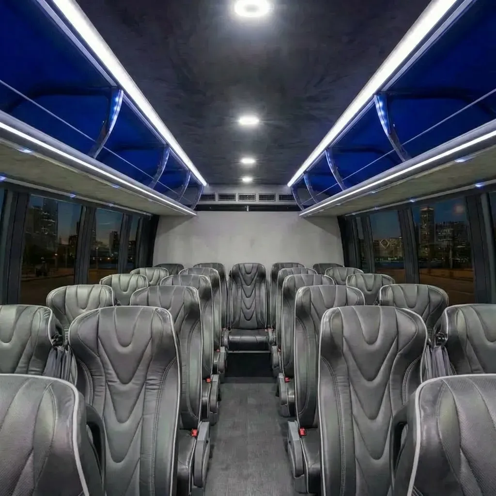 Interior view of a bus with rows of black leather seats, city view out windows, and overhead lighting.