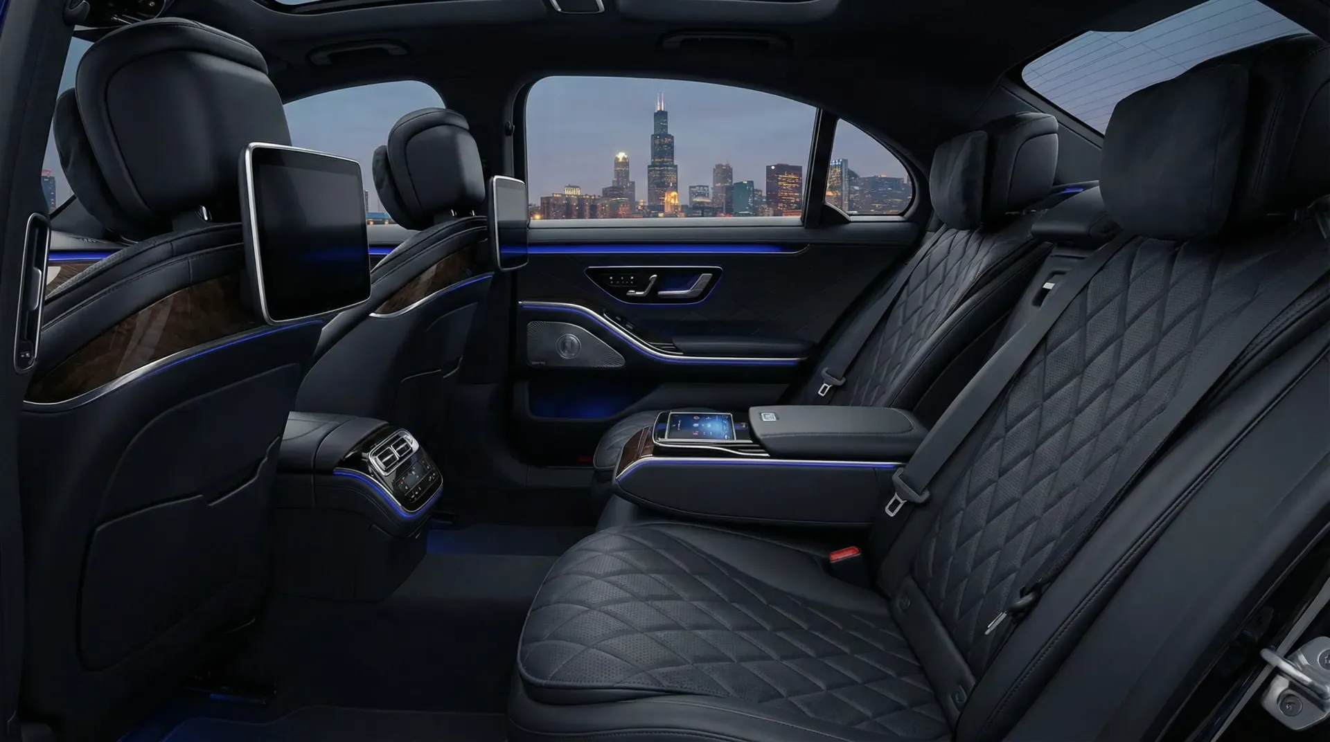 Interior view of a Mercedes S550 with black leather upholstery, rear-seat infotainment screens, and a city skyline view.