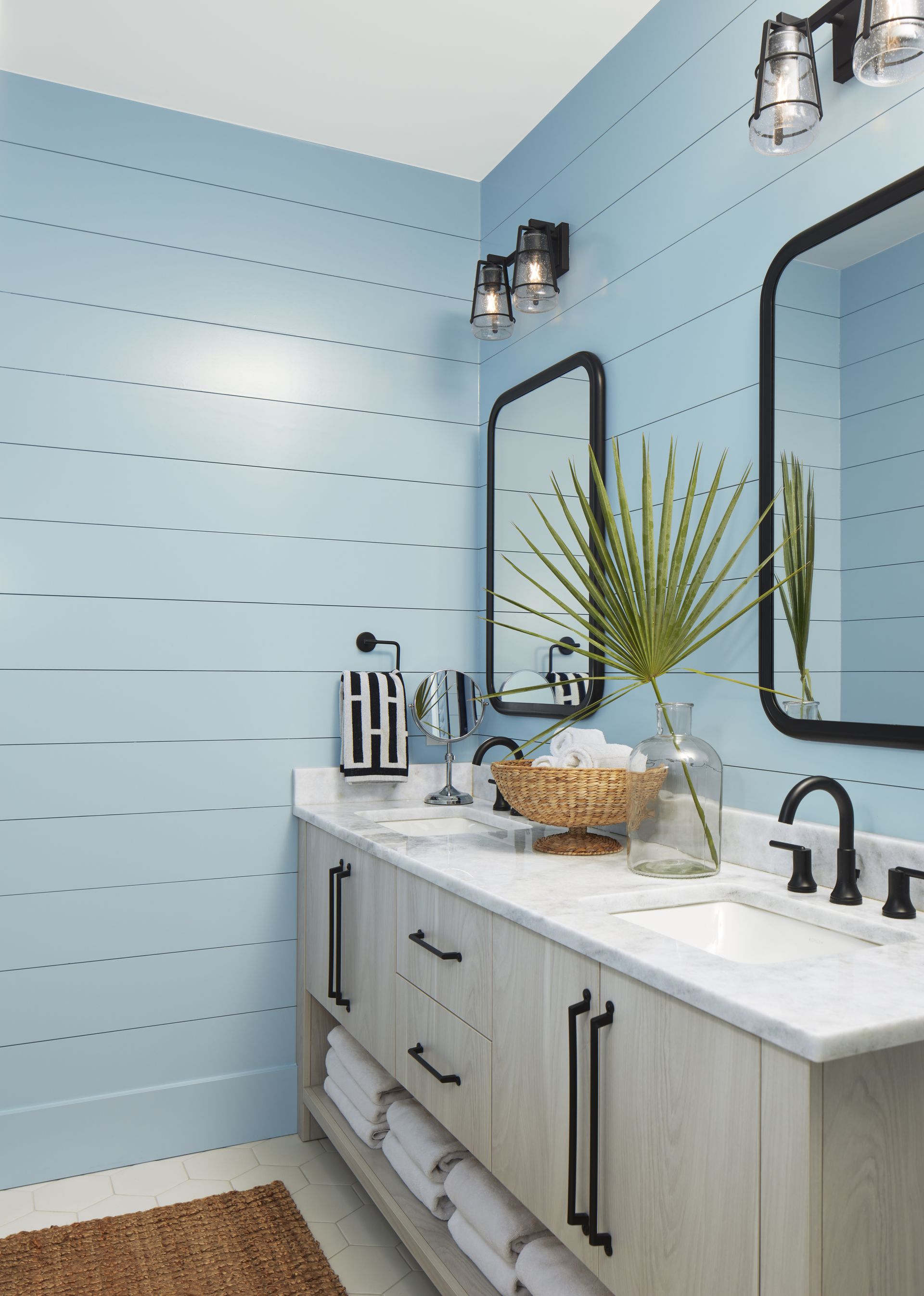 Modern bathroom vanity with light blue walls, double mirrors, and a white countertop with decor