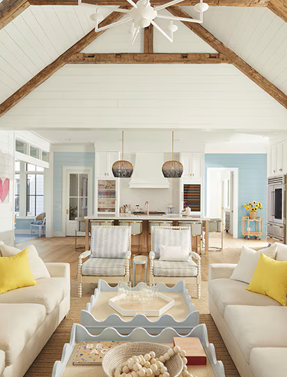 Bright airy living room with beige sofas, striped chairs, and a vaulted wood ceiling