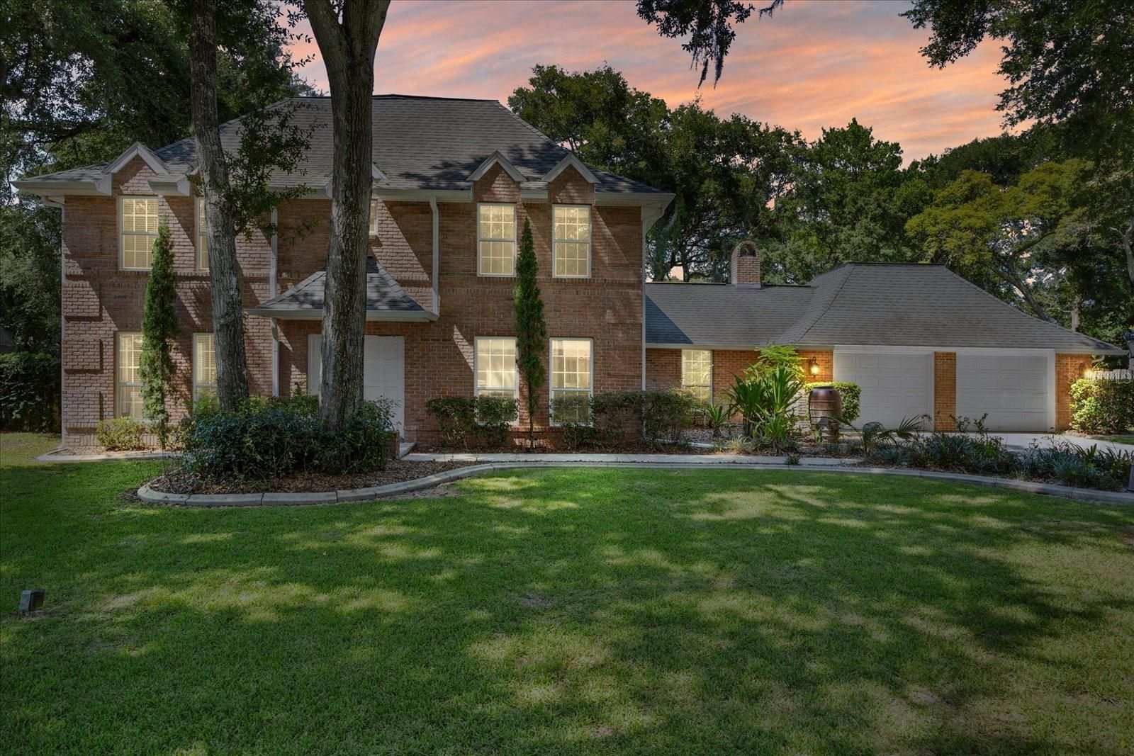 A large brick house with a large lawn in front of it
