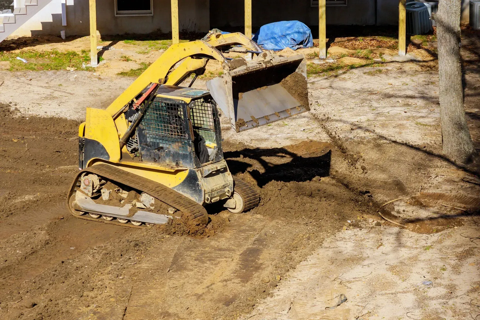 Yellow skid-steer loader digging dirt at a construction site