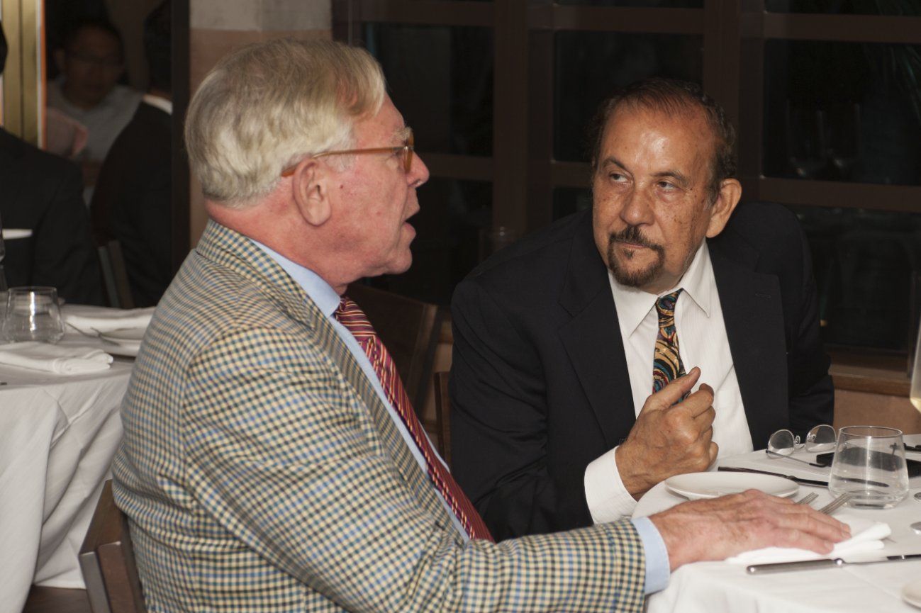 Two men are sitting at a table talking to each other