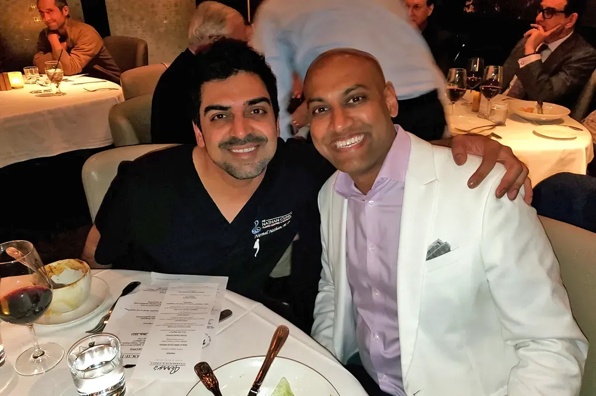 Two men are posing for a picture while sitting at a table