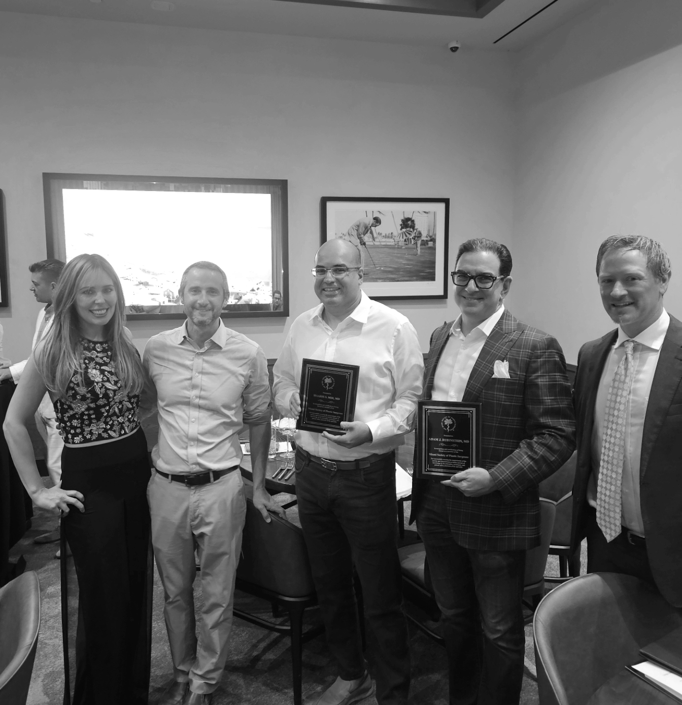 A group of people standing next to each other in a room holding awards.